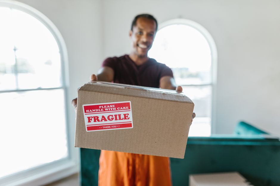 Smiling professional mover holding a neatly packed box