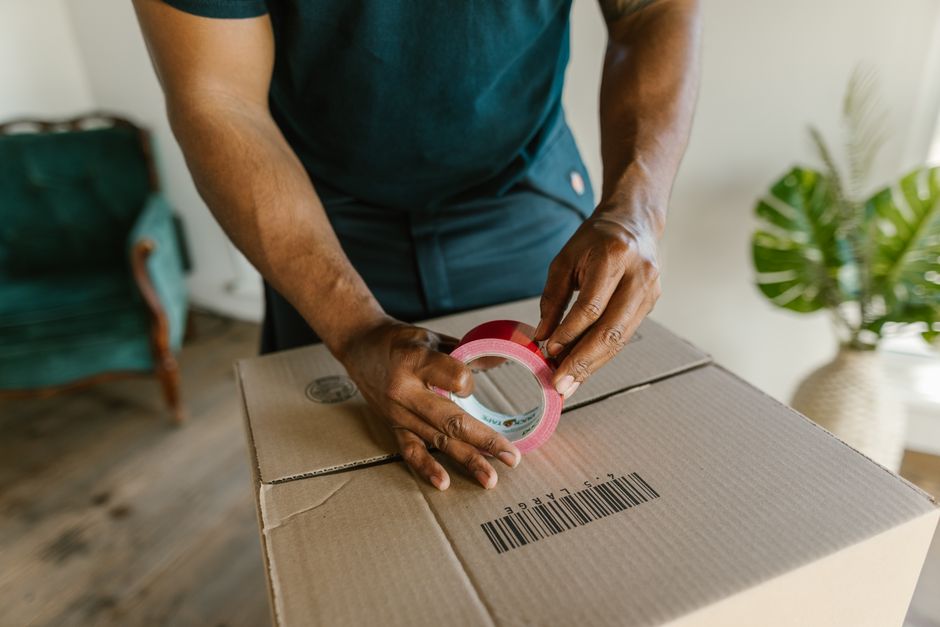 Mover taping a cardboard moving box